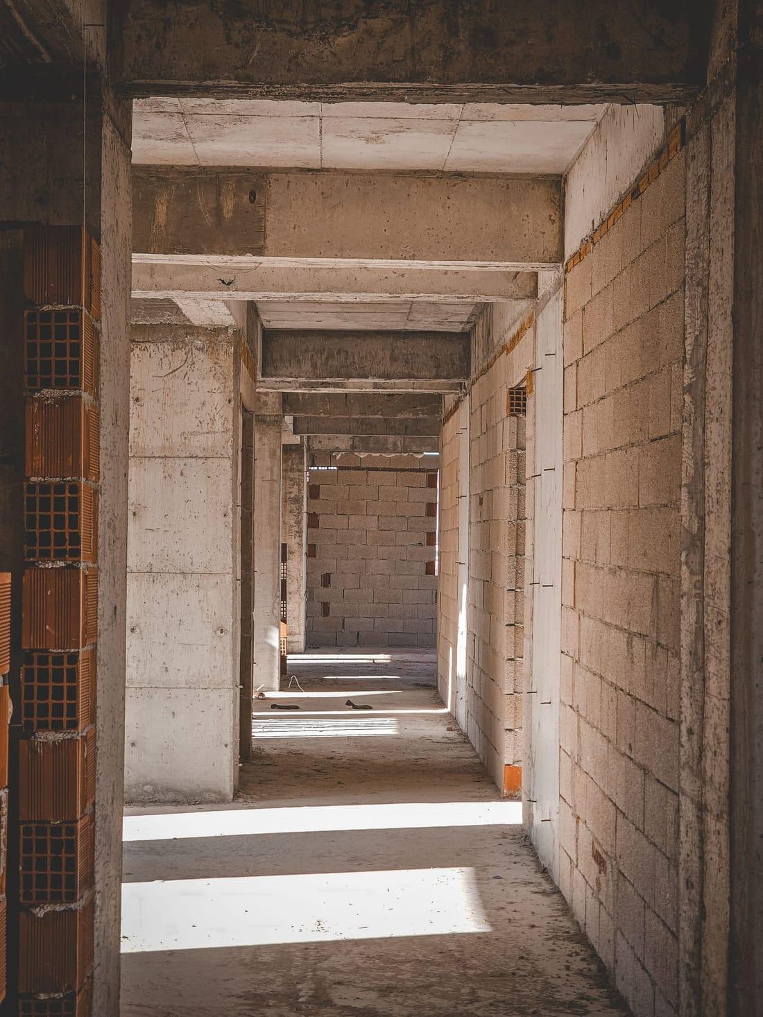 Coridor într-o casă la roșu: stâlpi și grinzi de beton armat, pereți din blocuri de zidărie și cărămidă termoizolantă, fără niciun finisaj