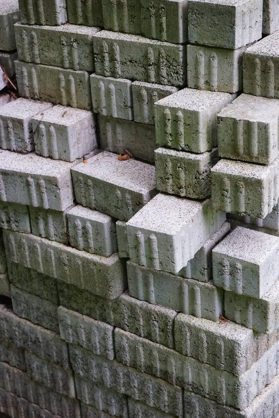 Stivă de pavele de beton gri, așezate în rânduri, depozitate în curte înainte de montaj